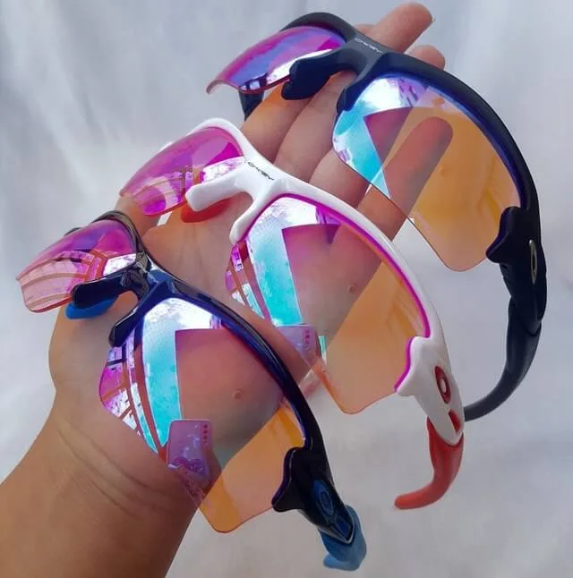 Três óculos esportivos com lentes refletivas coloridas, ideais para atividades ao ar livre e proteção solar.