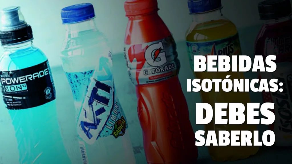 Una variedad de botellas de bebidas isotónicas de diferentes marcas y colores (Powerade azul, Gatorade roja y Aquarius amarilla) alineadas sobre un fondo claro, con el texto en español "BEBIDAS ISOTÓNICAS: DEBES SABERLO" superpuesto a la derecha.