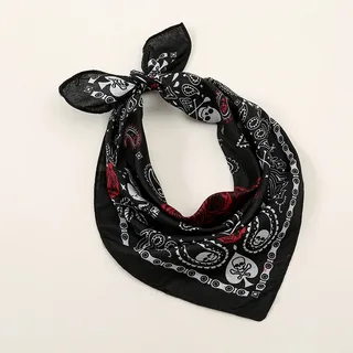 Bandana preta com estampa de caveiras, rosas vermelhas e padrões paisley em branco e vermelho, amarrada em formato triangular com nó na ponta superior.