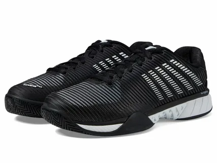 Par de tênis esportivos pretos com detalhes em branco e cinza, solado texturizado e design moderno, exibindo listras horizontais brancas nas laterais e cadarços pretos sobre fundo branco.