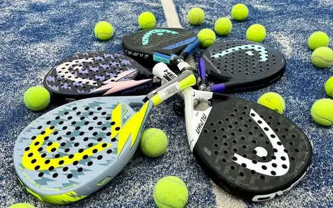 Quatro raquetes de padel da marca Head dispostas em círculo sobre uma quadra azul, cercadas por várias bolas amarelas de tênis.
