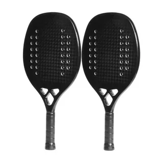 Duas raquetes de beach tennis pretas idênticas lado a lado, com superfície texturizada em padrão de fibra de carbono e furos circulares simétricos, empunhadura preta com fita de aderência e design minimalista.
