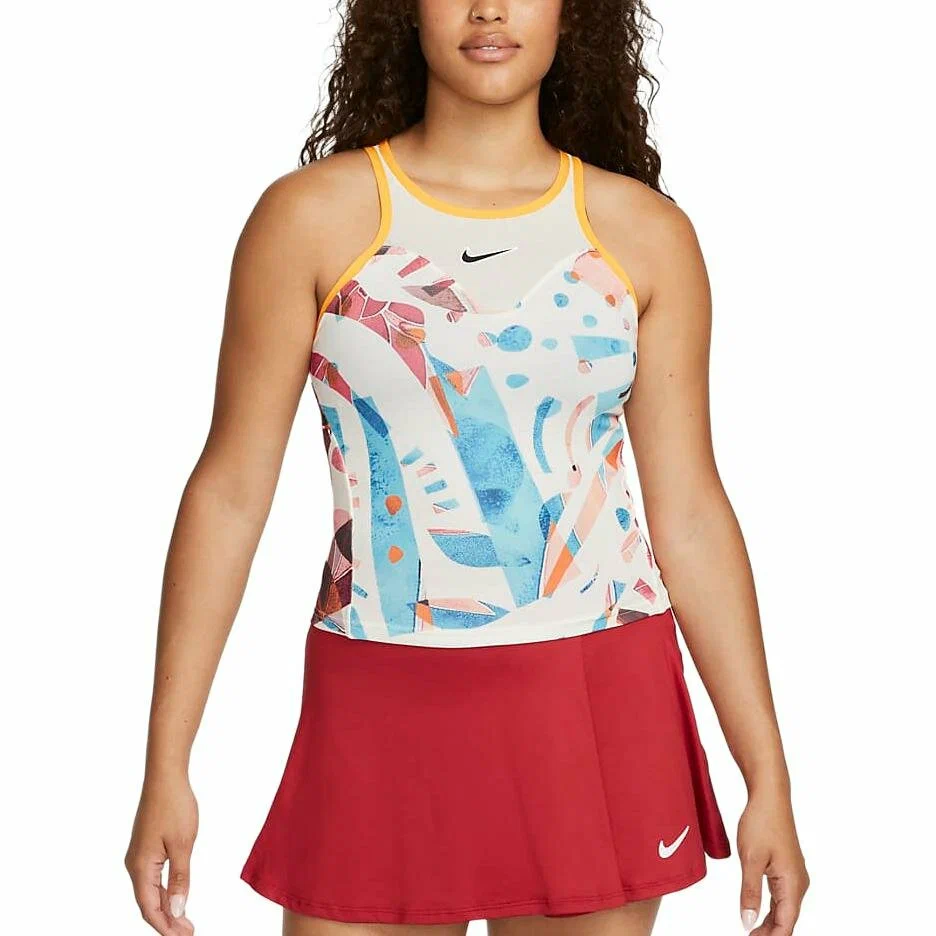 Mulher vestindo roupa esportiva da Nike composta por regata estampada com padrões abstratos em azul, vermelho e laranja, com bordas amarelas, e saia vermelha lisa com o logotipo branco da Nike.